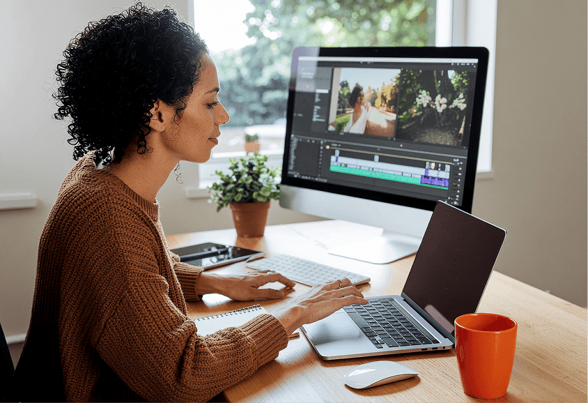 Digital creative woman working at desk with multiple monitors